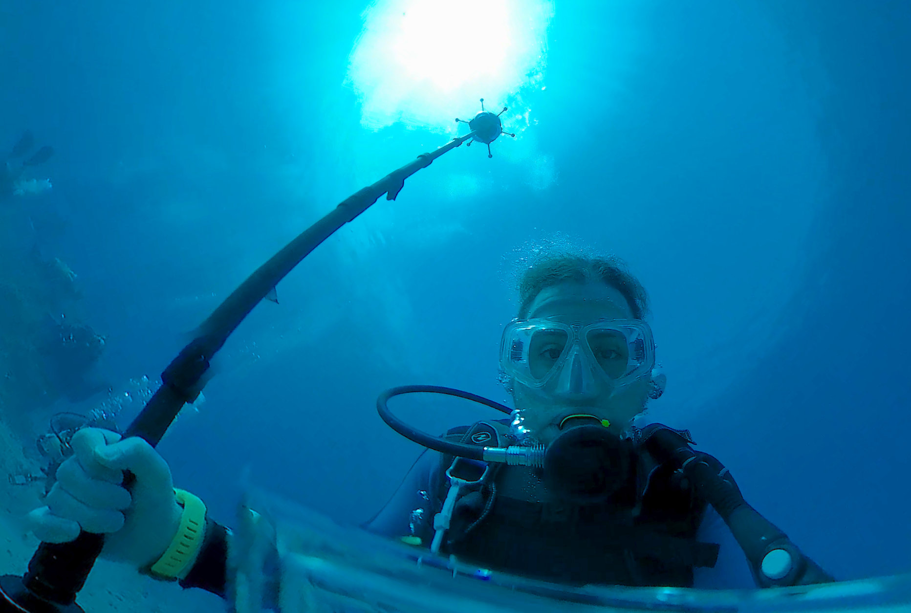 Underwater 360 video camera operator scuba diving with monopod mounted camera