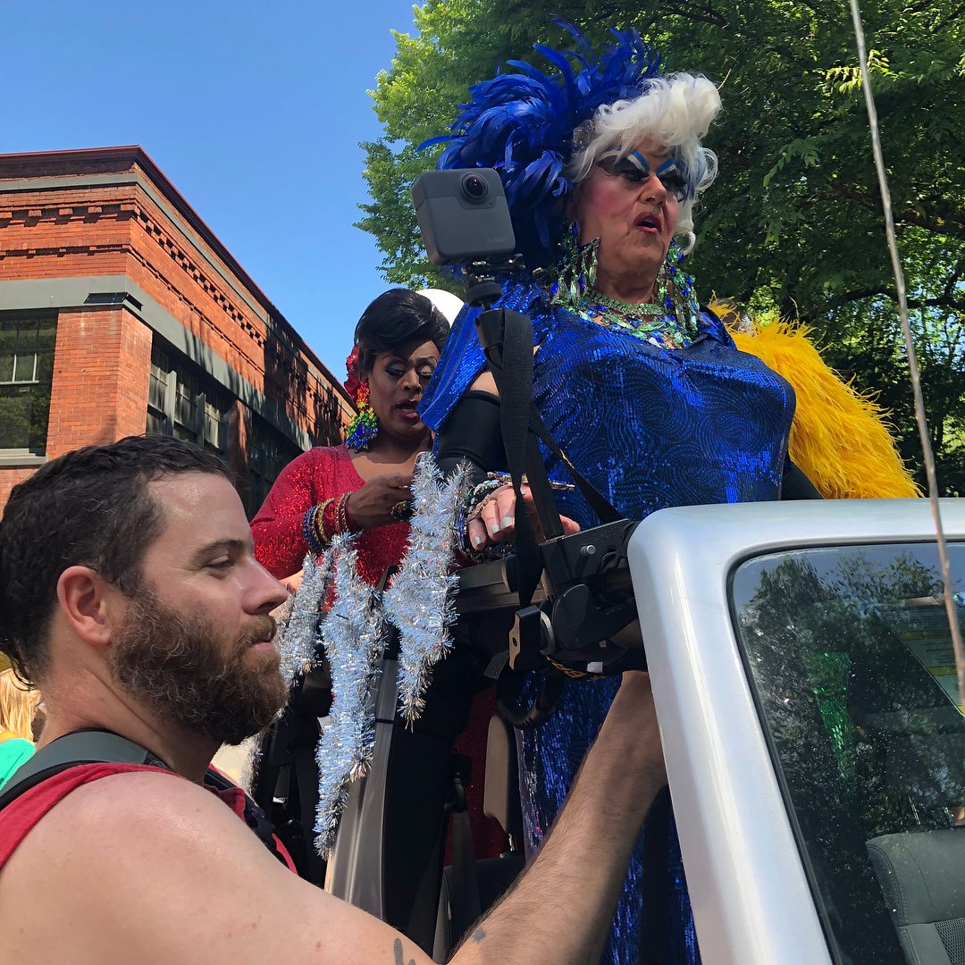 360 camera operator filming Pride parade event with Insta360 camera on monopod